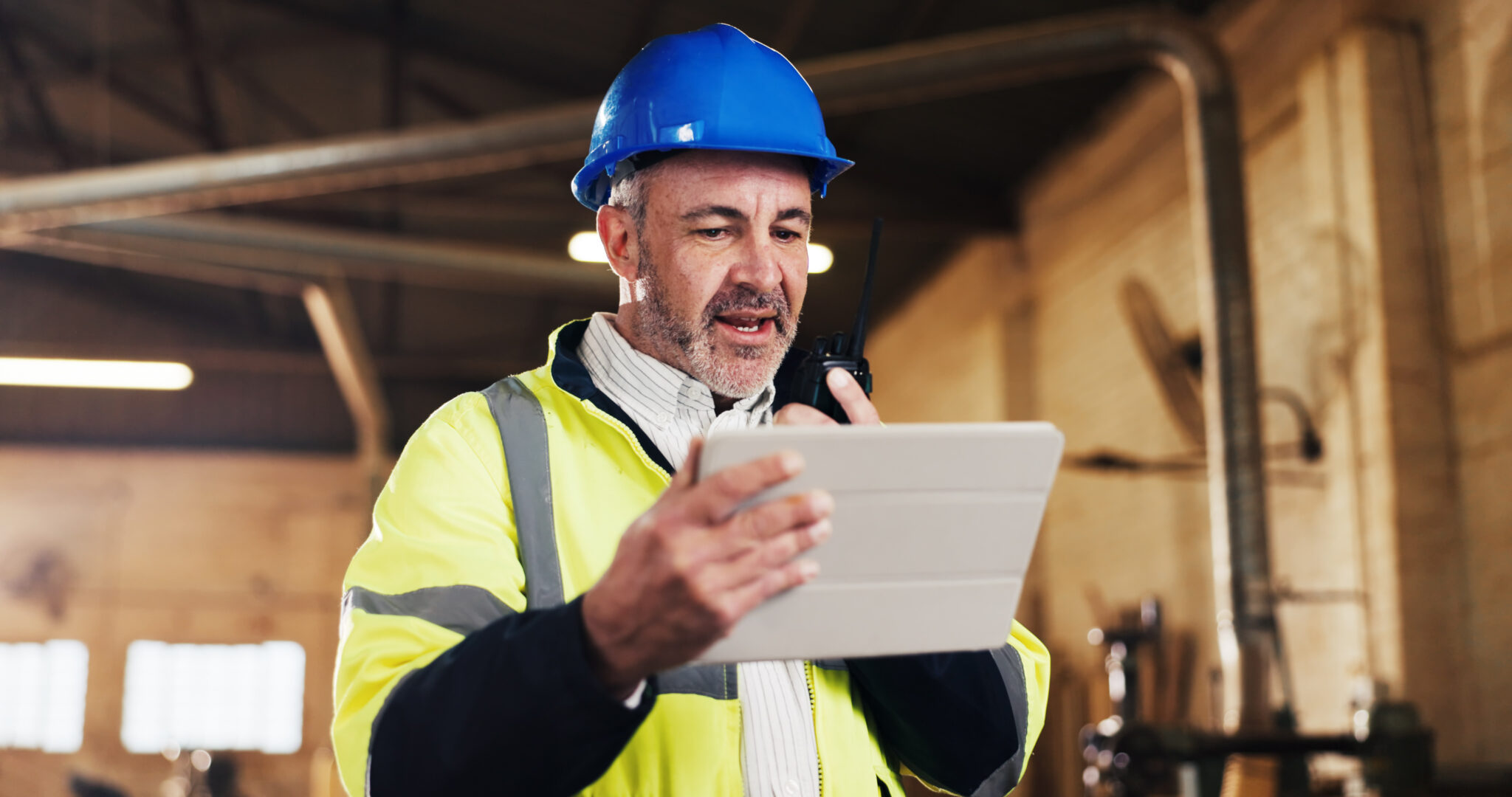 Uitvoerder gebruikt een tablet en portofoon om werkzaamheden in de buitendienst te coördineren.
