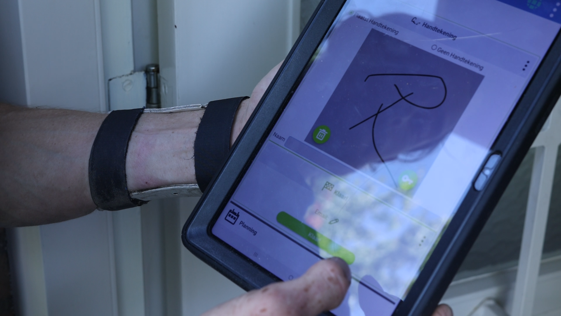 Klant zet een digitale handtekening op een werkbon in de Simple-Simon app op een tablet.