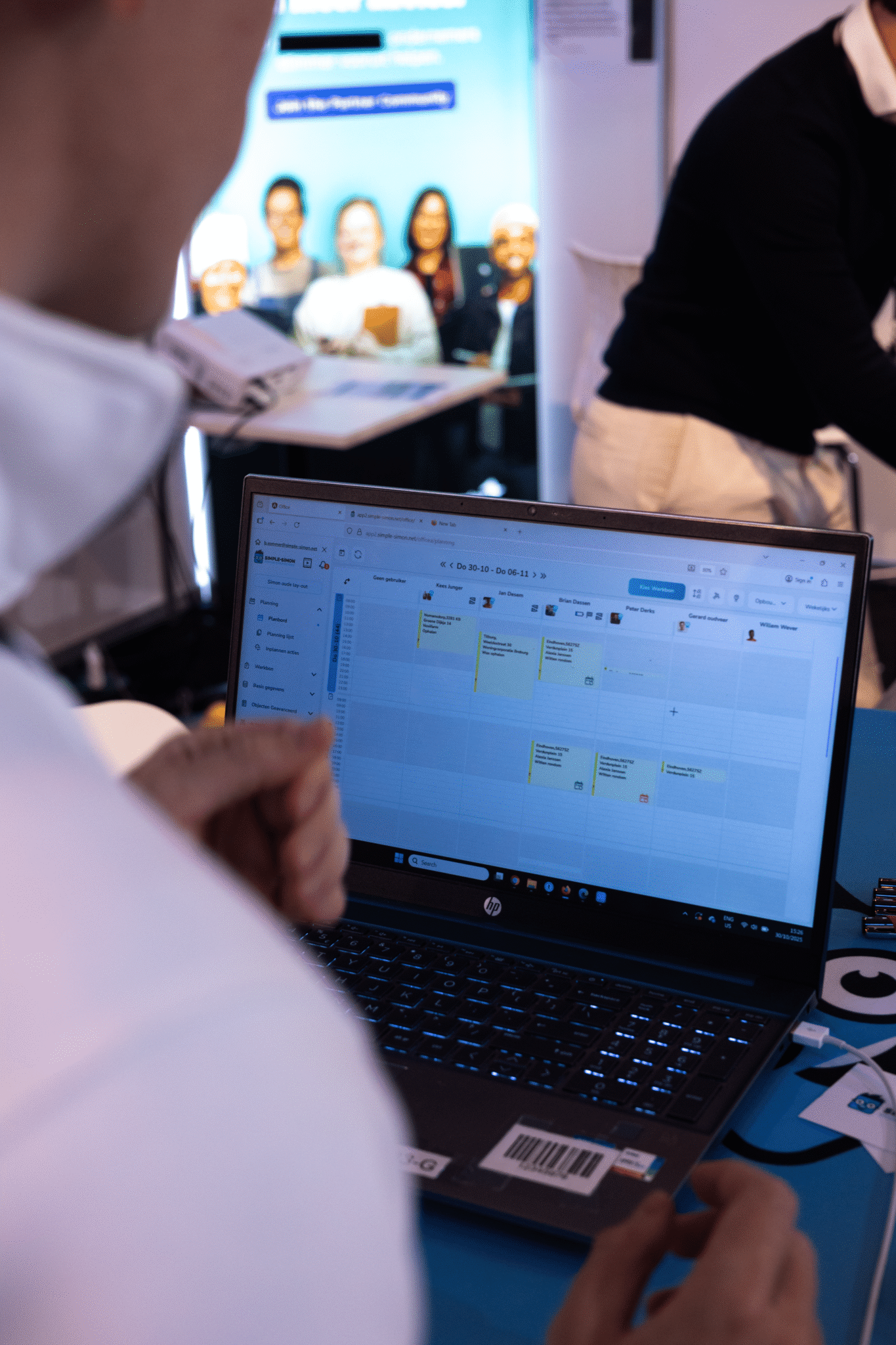 Bezoeker bekijkt een live demo van het digitale planbord van Simple-Simon op een laptop tijdens een vakbeurs.