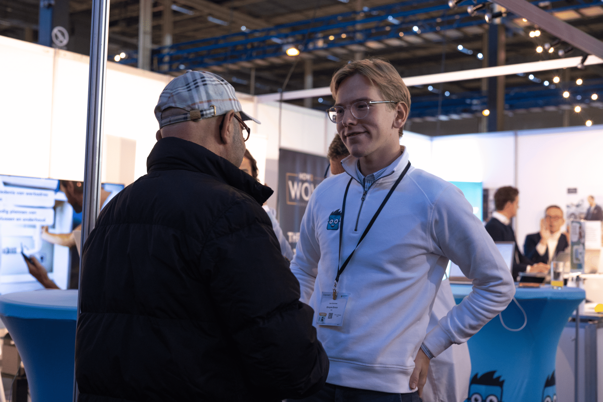 Medewerker van Simple-Simon in gesprek met een bezoeker tijdens een vakbeurs.