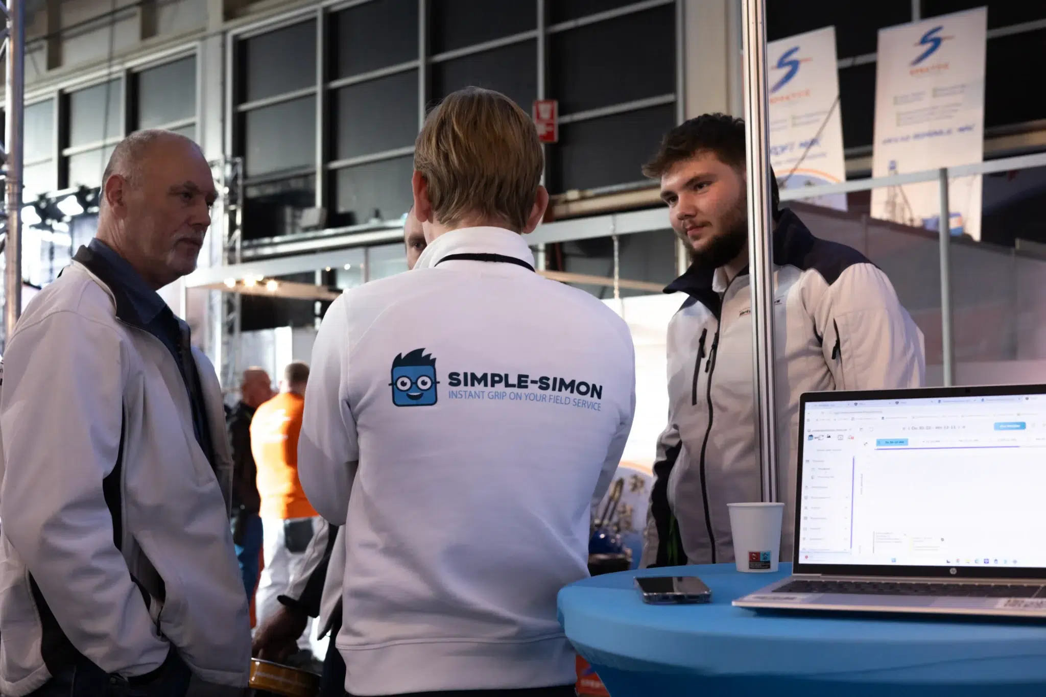 Simple-Simon medewerker in gesprek met bezoekers tijdens een vakbeurs.
