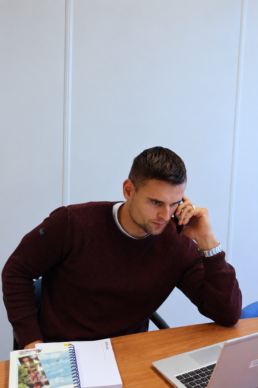 Medewerker voert telefonisch overleg terwijl hij achter zijn laptop werkt.