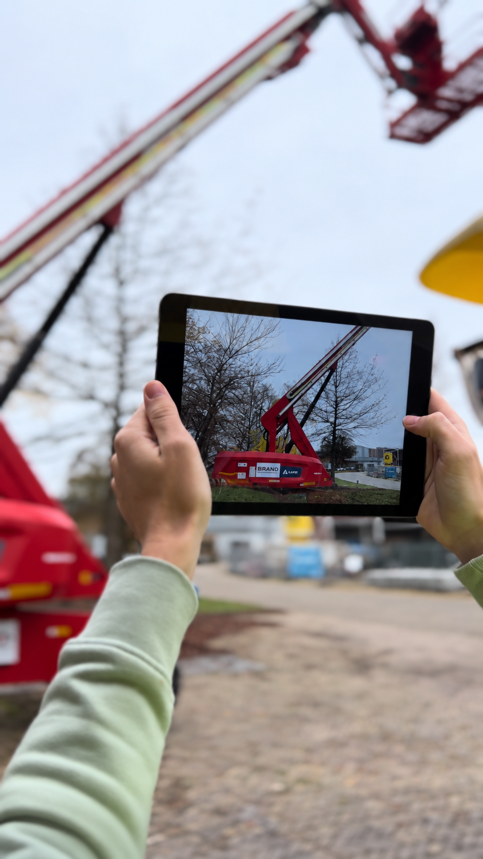 Monteur gebruikt een tablet om een hoogwerker digitaal te inspecteren.