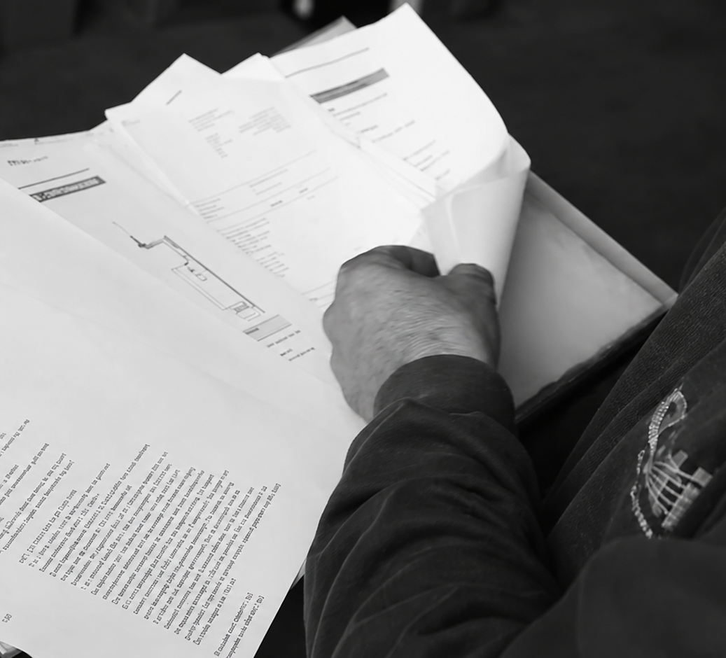 Monteur bekijkt technische documenten en tekeningen op papier.
